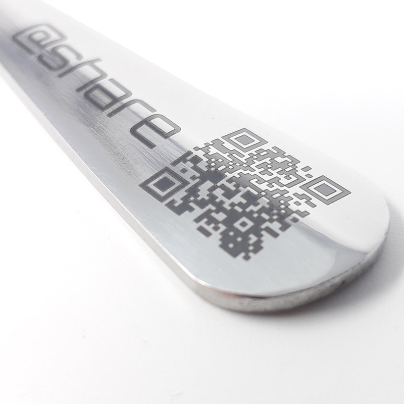 Close up of a laser engraved tea spoon with business name and social media details and a QR code